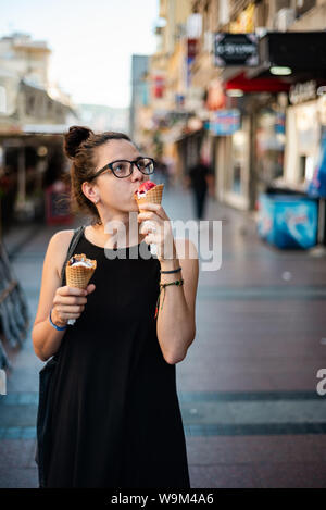 Hipster cute girl eating deux glaces dans la rue Banque D'Images