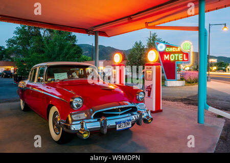 Crépuscule sur 1955 Studebaker President classic voiture garée en face de pompes à essence anciennes converties en chargeurs de voiture électrique ; l'Circle R Motel ; Salida Banque D'Images