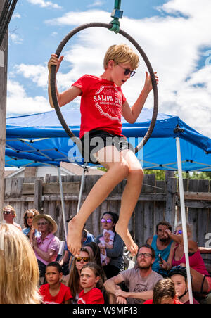 Jeune garçon effectuant sur anneaux cirque hoops Lyras ; Salida Circus summer camp finale ; Salida, Colorado, USA Banque D'Images