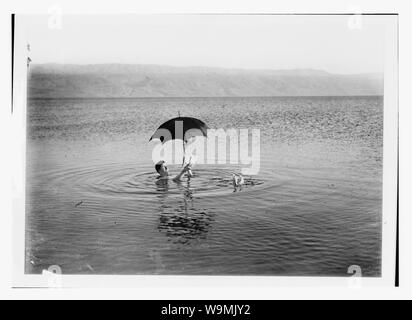 Autour de la Mer Morte. Homme flottante par livre et parapluie dans ses mains Banque D'Images