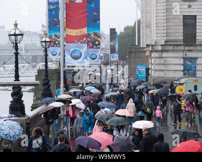 Londres, Royaume-Uni. 14 août, 2019. Les touristes ne sont pas découragés par la pluie qu'on voit ici sur la rive sud de Londres près de London Eye, ce début de soirée. Crédit : Joe Keurig / Alamy News Banque D'Images