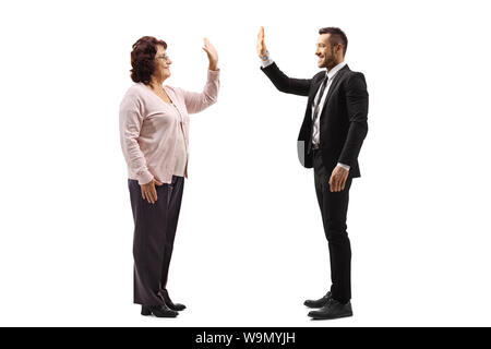 Profil de pleine longueur de balle a senior woman gesturing high-cinq avec un jeune homme en costume isolé sur fond blanc Banque D'Images