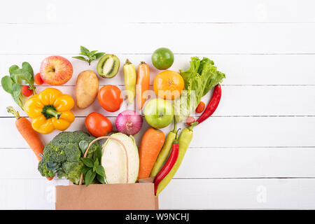 Style de vie sain et de l'alimentation de concept. Vue de dessus sac de papier de différents légumes frais sur fond de bois blanc. Mise à plat. Banque D'Images