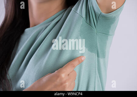 Gros plan femme asiatique avec l'hyperhidrose la transpiration. Jeune femme d'Asie de sueur tache sur ses vêtements contre un arrière-plan gris. Concept de soins de santé. Banque D'Images