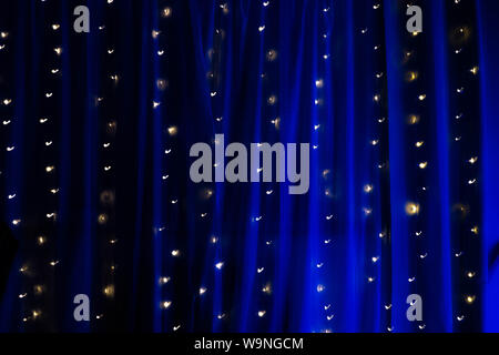 L'exposition longue chaîne de fairy lights sur rideau lumineux bleu , fond Banque D'Images
