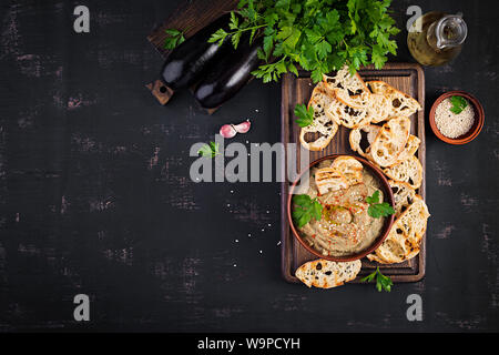 Baba Ghanoush hoummos vegan aubergine avec de l'assaisonnement, le persil et le pain grillé. Baba ganoush. Une cuisine du Moyen-Orient. Vue de dessus, les frais généraux Banque D'Images