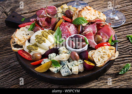 L'antipasto platter avec jambon, jambon, salami, fromage bleu, mozzarella au pesto et olives sur un fond de bois. Banque D'Images
