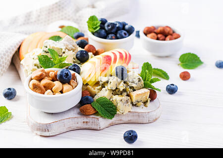 Assiette de fromage avec un assortiment de fromages, de myrtilles, pommes, noix sur tableau blanc. Plateau de fromages italiens et de fruits. Banque D'Images