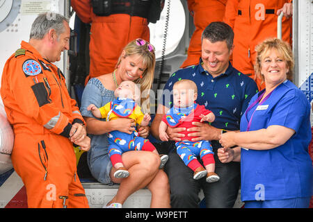 Jennie et riche Powell avec leurs jumeaux Jenson, gauche, Ruben, droite, qui célèbrent leur premier anniversaire en rencontrant les équipes de garde-côtes HM pour la première fois depuis que Jennie a été évacué par eux dans un hélicoptère à Oxford de Cornouailles après qu'elle entre en travail à 22 semaines avec ses jumeaux, l'accouchement le plus jeune avant terme survivant des jumeaux nés en Grande-Bretagne. Sur la photo (de gauche à droite) Le chef d'équipage Ian Copley, Jennie, Jenson, Ruben, riche et sage-femme Jane Parke qui ont accompagné le vol sur Jennie. Banque D'Images