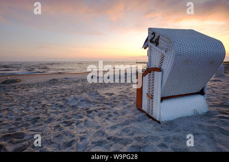 Lever du soleil sur la côte de la mer Baltique,la chaise de plage se trouve sur la plage de sable. Banque D'Images