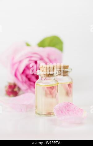 Deux flacons à l'huile essentielle et rose rose fleur sont sur un fond blanc Banque D'Images