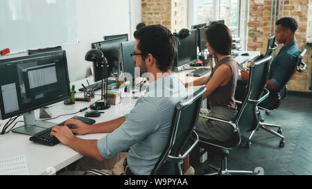 De l'équipe multiraciale. Vue arrière d'employés occupés à travailler sur les ordinateurs alors que sitting at desk in modern espace ouvert. Concept d'emploi. Lieu de travail. Le travail d'équipe Banque D'Images