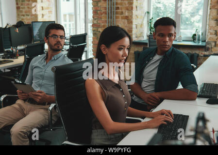 Réunion rapide. Groupe de travail sur les jeunes employés gais et de discuter les ordinateurs des tâches quotidiennes tout en étant assis dans un espace ouvert. Concept d'emploi. Les gens d'affaires. Lieu de travail Banque D'Images