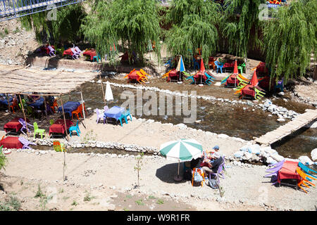 Les gens s'assoient dans des restaurants sur la rivière à Sti Fadma, vallée de l'Ourika dans les montagnes de l'Atlas, Maroc Banque D'Images