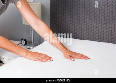 Woman's hands close-up faire le lit. Femme de ménage la modification du lin. Banque D'Images