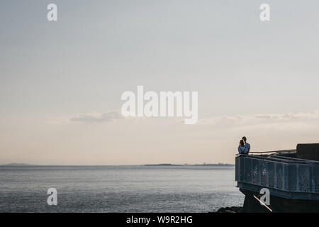 Lymington, Royaume-Uni - Juillet 13, 2019 : Couple au bord de la mer au coucher du soleil à Milford on Sea, un village traditionnel anglais célèbre pour une falaise wal Banque D'Images