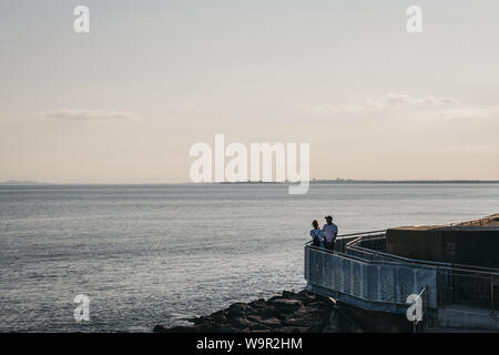 Lymington, Royaume-Uni - Juillet 13, 2019 : Couple au bord de la mer au coucher du soleil à Milford on Sea, un village traditionnel anglais célèbre pour une falaise wal Banque D'Images