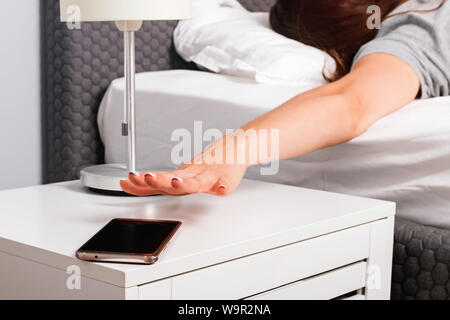 Woman's hand close-up d'essayer de tendre la main en sonnerie de téléphone portable ou d'avoir une certaine alarme répét tôt le matin. Banque D'Images