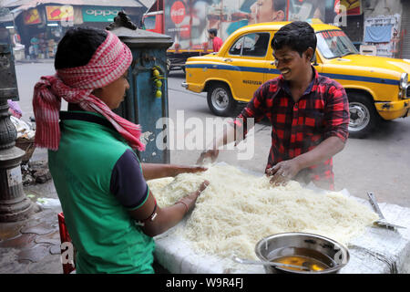 Les jeunes vendeurs au marché de préparer la nourriture dans un food à Kolkata, Inde Banque D'Images