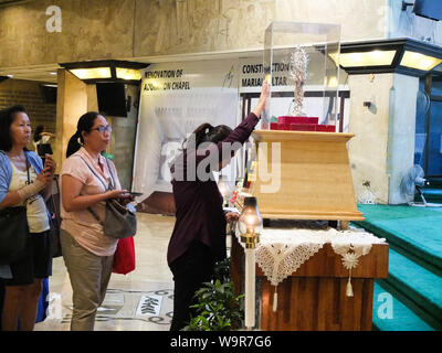 Quezon City, Philippines. 14Th Aug 2019. Une femme prie avec ferveur dévote en touchant le verre contenant de la relique de Saint Jean Paul II.dévots catholiques affluent pour Sanctuaire de Marie, Reine de la paix (EDSA) Notre Dame de l'adoration perpétuelle chapelle dans Ortigas Avenue, Quezon City aux Philippines pour vénérer la relique du sang de Saint Jean Paul II. La vénération a fait partie de la célébration de la jeunesse avec le thème "Les jeunes Philippins dans Mission : bien-aimé, doué et pouvoir'. Credit : SOPA/Alamy Images Limited Live News Banque D'Images