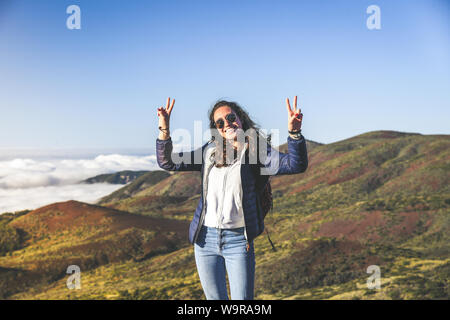 Smiling adolescent avec les mains posées sur le haut de la montagne. Belle vue sur la mer forêt et nuages en arrière-plan. Volcan Teide, Tenerife Banque D'Images