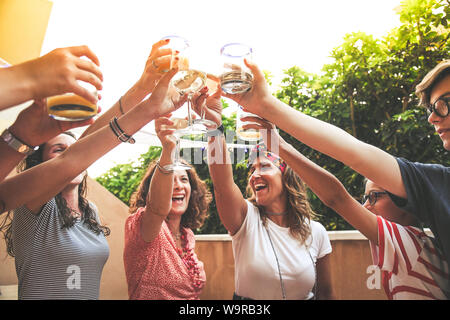 Groupe d'amis heureux avec des lunettes d'encouragement au dîner en terrasse en plein air. Adolescent et les mères s'amuser tout en buvant et en mangeant. Se concentrer sur des verres Banque D'Images