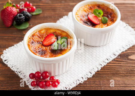 Délicieux café-noisette crème brûlée servi en ramequin blanc avec avec les baies fraîches et de feuilles de menthe Banque D'Images