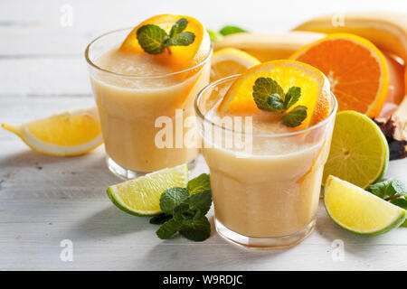 Banane fraîchement mélangé et agrumes smoothie ou milk-shake dans deux verres d'ingrédients secs. Des vitamines, des boissons de fruits rafraîchissant Banque D'Images