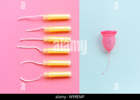 La coupe menstruelle féminine est en contraste avec les tampons six dans les applicateurs. Banque D'Images