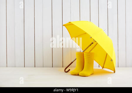 Une paire de bottes de pluie jaune et un parapluie sur fond de bois Banque D'Images