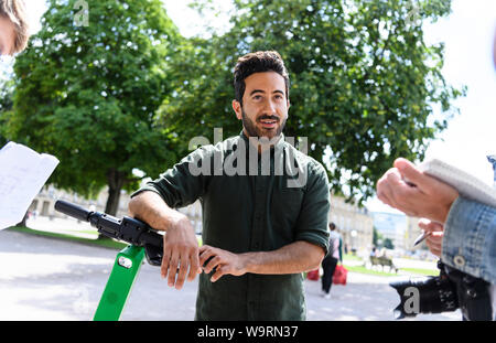 15 août 2019, Bade-Wurtemberg, Stuttgart : Jashar Seyfi, chef de l'e-tretroller Lime fournisseur en Allemagne, est debout près d'un scooter à l'occasion du lancement du prestataire à Stuttgart. La première des scooters ont été mis en place le jeudi (15.08.2019) par la filiale allemande de la société américaine de la chaux à un endroit convenu avec la municipalité. Photo : Edith Geuppert/dpa Banque D'Images