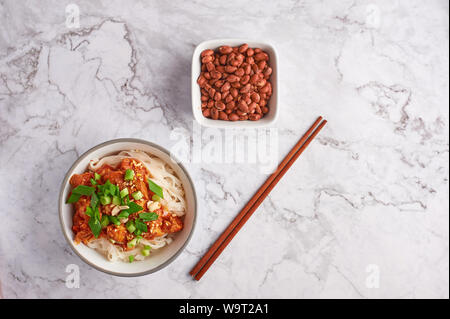 Nouilles shan avec arachides et baguettes à table en marbre blanc. La cuisine birmane myanmar plat traditionnel. la nourriture. les nouilles de riz avec du porc dans les tomates Banque D'Images