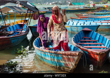 Les femmes de sortir d'un petit bateau de pêche sur le lac à Pokhara Banque D'Images