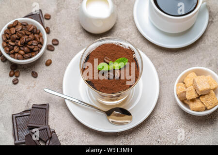 Dessert tiramisu classique dans un verre, café, chocolat, crème et sucre sur fond de béton Banque D'Images