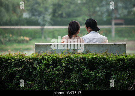 Jeune couple népalais s'assit sur un banc à écouter de la musique. Banque D'Images