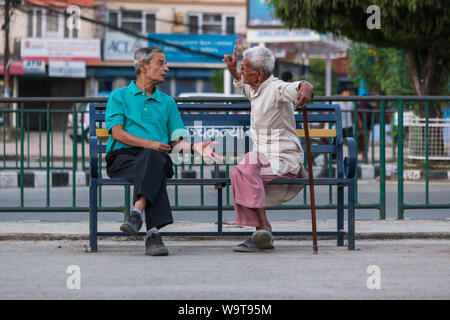 Les hommes assis sur un banc de parc à Pokhara un débat. Banque D'Images