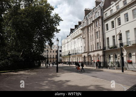 Les piétons s'occuper de leurs affaires sur une journée d'été, Fitzroy Square, Londres. Banque D'Images