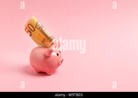 Pink piggy bank avec cinquante euros sur un fond rose. Banque D'Images