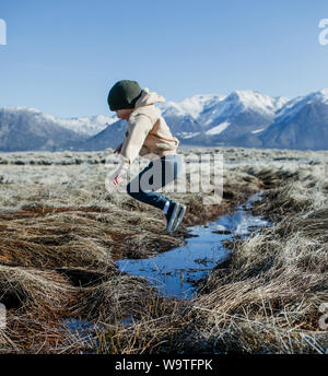 Garçon sautant au dessus d'un ruisseau, Mammoth Lakes, California, United States Banque D'Images