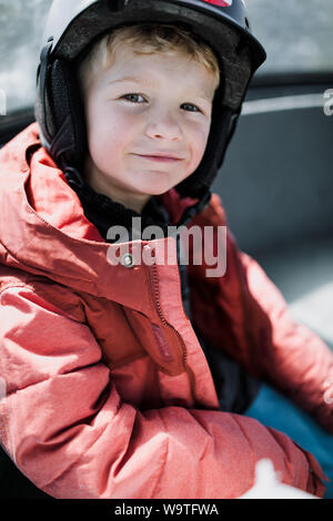 Portrait of a smiling boy sitting in a gondola portant un casque de ski, Mammoth Lakes, California, United States Banque D'Images