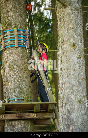 Un garçon se tient sur une plate-forme dans un cours d'highrope Banque D'Images