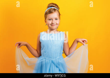 Charmante petite fille dans un costume de princesse Cinderella sur un fond de couleur jaune. Concept pour l'automne, halloween, maison de vacances. Banque D'Images