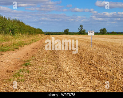 Une route privée. Pas d'accès sans autorisation de signer sur un post sur le côté d'une ferme la voie à côté d'un champ de chaumes arables Banque D'Images
