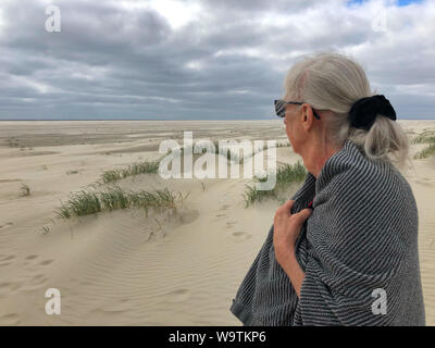 Senior woman à la plage dans une serviette après une baignade, adresses importantes Tidevand Færgeruter Lufthavne Bil, Danemark Banque D'Images