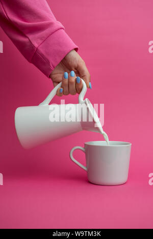 Woman pouring un pichet de lait dans une tasse Banque D'Images