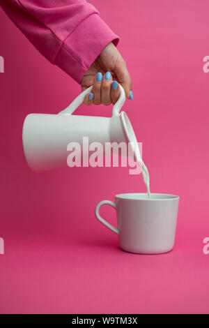 Woman pouring un pichet de lait dans une tasse Banque D'Images