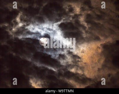 La lueur de la pleine lune s'allume de façon dramatique nuages dans un ciel de nuit. Banque D'Images