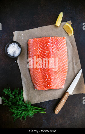 Vue de dessus du filet de saumon cru frais avec l'aneth, sel de mer et de citron sur une table pour la cuisine. Recette pour le régime cétogène ou régime paléo. Banque D'Images