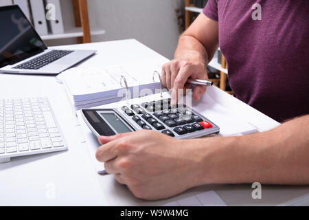 Close-up de la main d'affaires Le calcul de l'impôt à l'aide de la facture sur Calculatrice Desk In Office Banque D'Images