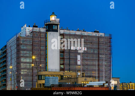 Phare éclairé avec un bâtiment en construction à l'arrière-plan, l'architecture à la côte de Blankenberge, Belgique, le 15 février, 2019 Banque D'Images